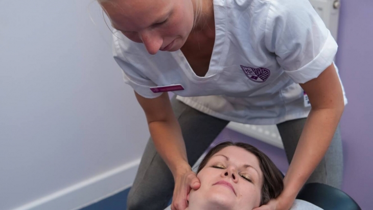 A female chiropractor treating a female patients neck in a treatment room